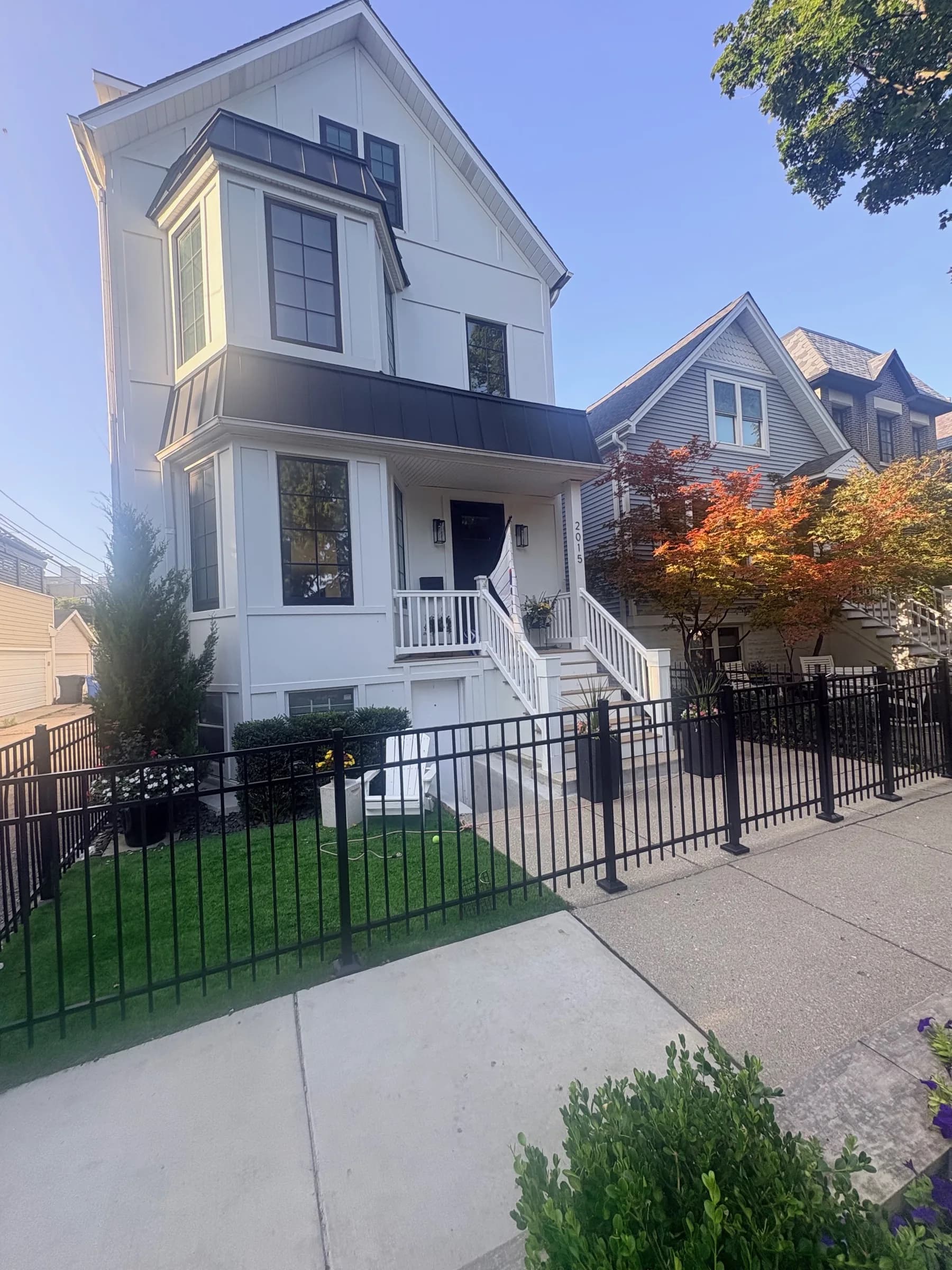 Front of the house: white board-and-batten coach house with black trim and a fenced front yard